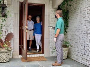 man in gloves and mask meeting clients at door